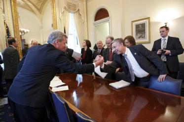 Something that doesn't happen enough: compromise. Sen. Max Baucus (D) of Montana, left, reaches across the table to shake hands with Rep. Fred Upton (R) of Michigan after bipartisan House and Senate conferees signed a compromise agreement on the payroll tax cut extension. Image by  J. Scott Applewhite/AP.