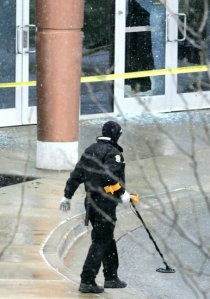 A crime scene investigator uses a metal detector Sunday at the shooting scene at the Jewish Community Campus in Overland Park, Kan. Image by Fred Blocher, Kansas City Star.