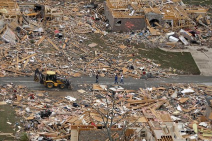 People walk between two destroyed houses in Mayflower on Monday. Image by Danny Johnston/AP.