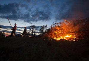 People tend a fire to clear debris in Vilonia. Image by Carlo Allegri, Reuters.