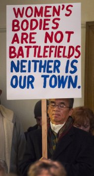 Dennis Apuan holds a sign during a vigil at the All Souls Unitarian Universalist Church for those killed in Friday's shooting. Image by Christian Murdock/The Gazette via AP.